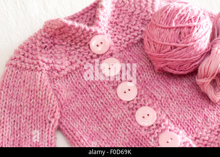 Lavorate a maglia rosa baby giacca di lana con pulsanti di grandi dimensioni, con sfera di filo sul lato Foto Stock