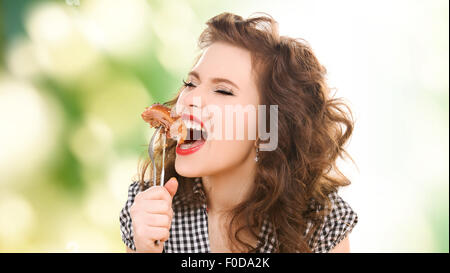 Fame giovane donna di mangiare carne sulla forcella su verde Foto Stock