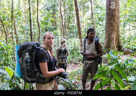 Tourist, escursionista giovane donna con uno zaino nella giungla con due Orang Asil uomini, Taman Negara, Malaysia Foto Stock