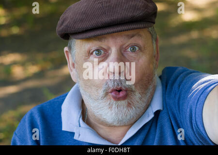 Ritratto di un uomo anziano chiedendo e facendo prima selfie nella sua vita Foto Stock