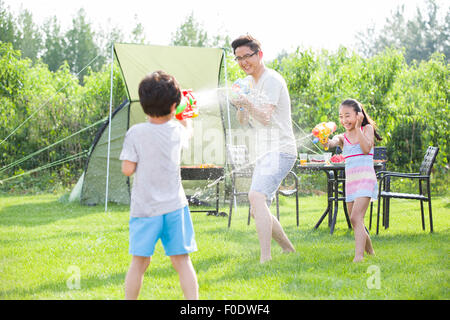 Padre Felice e i bambini giocando squirt pistole Foto Stock