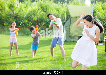 Felice famiglia giovane giocando squirt pistole Foto Stock