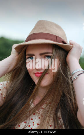 Bella ragazza adolescente tirando il suo cappello Foto Stock