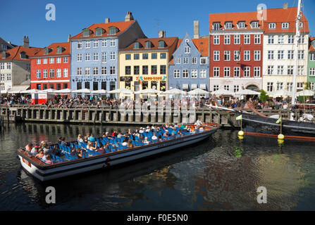 Canal tour in barca girando intorno nelle affollate Nyhavn canal su una calda e soleggiata giornata estiva piena di turisti e visitatori. Foto Stock