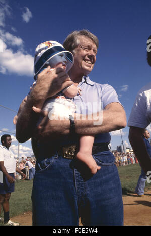 Le pianure, Georgia, Stati Uniti d'America. Il 2 gennaio, 1977. Jimmy Carter tiene il bambino di un amico ad una partita di pallavolo in pianura, Georgia. © Ken Hawkins/ZUMA filo/Alamy Live News Foto Stock