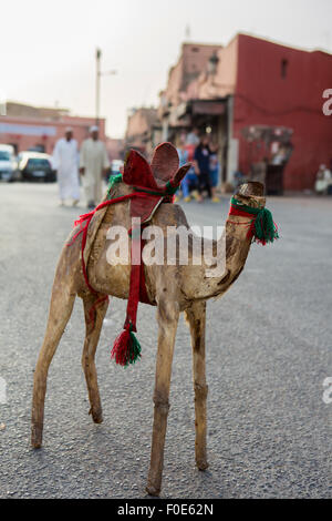 Camel giocattolo con testina rotti sul mercato aperto nella posa di Marrakesh sulla strada con due islamica uomini vestiti in background Foto Stock