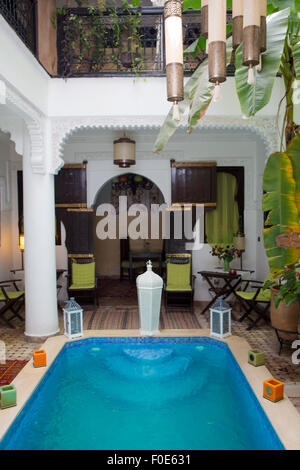 Vista interna di una casa araba interno con piscina e arredi tradizionali, tappeti, Marrakech, Marocco Foto Stock