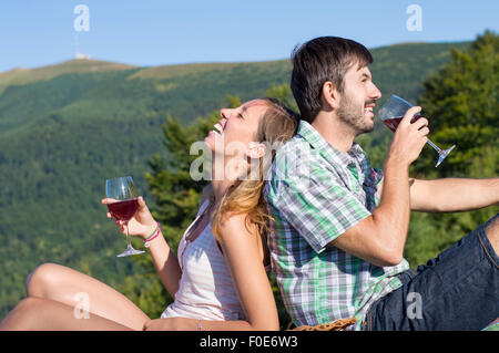 Giovane coppia felice di bere vino su una escursione presso il punto di vista. Escursionismo coppia viaggio Foto Stock