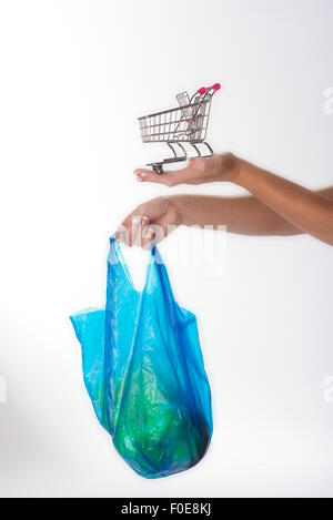 Donna che mantiene piccolo carrello per supermercati e plastica shopping bag Foto Stock