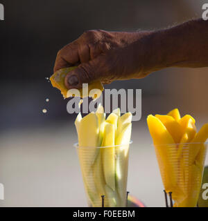 Spremitura a mano un agrume giallo su pezzi di melone a Cartagena, Colombia 2014. Foto Stock