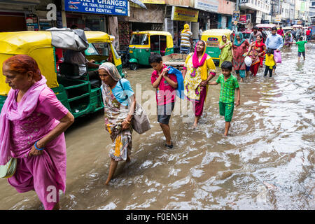 Persone e risciò ciclo si stanno spostando attraverso le strade inondate del sobborgo Paharganj dopo un pesanti piogge monsoniche Foto Stock