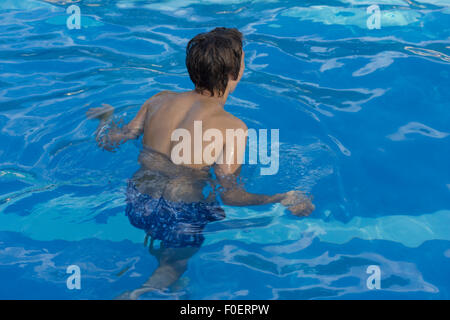 Giovane uomo alzarsi in piedi in una piscina Foto Stock