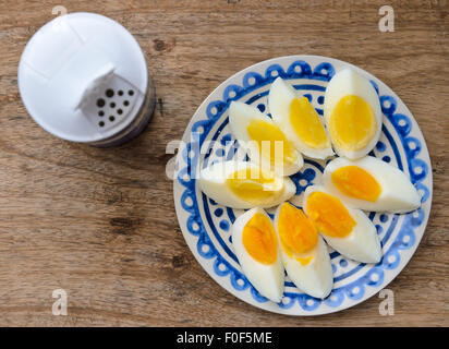 Due colori tuorlo, uova sode a fette in un blu lastra decorata in legno tavolo da cucina. Foto Stock