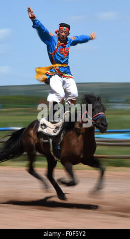 Ordos, la Cina della Mongolia Interna Regione Autonoma. 14 Ago, 2015. Un uomo mongolo sorge su un cavallo in esecuzione presso il mausoleo di Gengis Khan in Ejin Horo Banner, a nord della Cina di Mongolia Interna Regione Autonoma, 14 agosto 2015. Durante il tempo del decimo Nazionale Giochi tradizionali delle minoranze etniche della Cina, pastori locali hanno presentato la loro equitazione competenze e eseguita ippica per visitatori presso il mausoleo di Gengis Khan, il 13esimo secolo guerriero mongolo e fondatore dell'Impero Mongolo, qui a Ordos venerdì. © Zhang Ailin/Xinhua/Alamy Live News Foto Stock