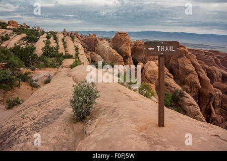 Lungo il Devils Garden Trail, escursionisti attraversare un lungo tratto di strette slick rock per raggiungere il doppio o Arch Foto Stock
