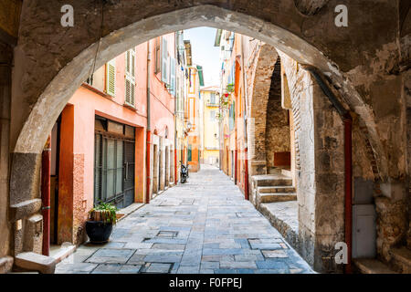 Stretta strada di ciottoli con i suoi edifici colorati visualizzati se arcata in pietra nella città medievale di Villefranche-sur-Mer sulla Rivie francese Foto Stock