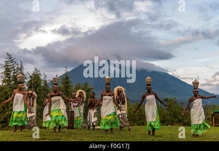 Ballerini locali di eseguire una danza tradizionale con Virunga montagne sullo sfondo parco Nazionale Vulcani Ruanda Africa Foto Stock