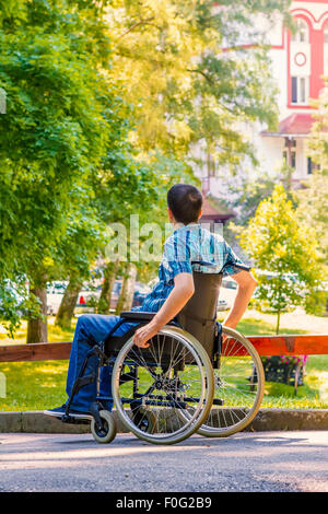 Giovane uomo in sedia a rotelle in city park Foto Stock