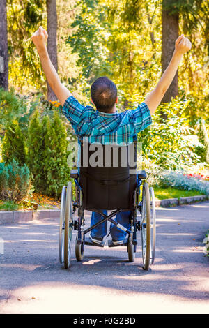Giovane uomo in carrozzella con ampia braccia aperte godendo la sua vita Foto Stock