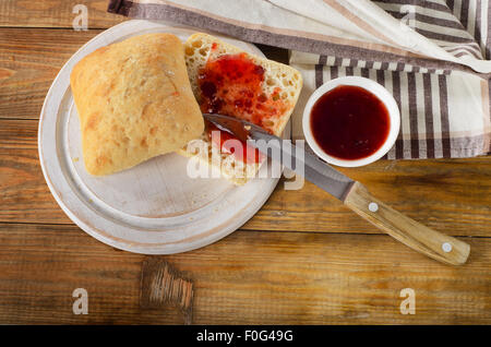 Pane fresco con confettura dolce sul bordo di taglio. Vista superiore Foto Stock