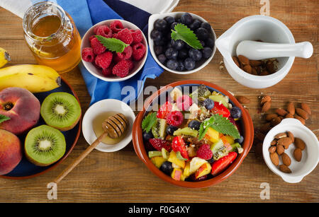In casa sana insalata di frutta fresca e bacche e frutti su legno rustico sfondo. Vista superiore Foto Stock