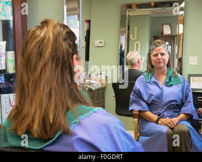 Parrucchiere proprietario di applicare il colore a Client femmina, Florida, Stati Uniti d'America Foto Stock