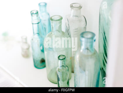 Più vintage di bottiglie di vetro su di un ripiano bianco, primo piano Foto Stock