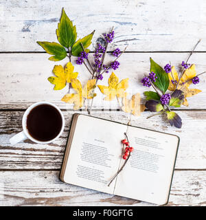 Libro aperto alla poesia di autunno da J. Keats, con la tazza di caffè, foglie e bacche Foto Stock
