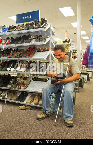 Salt Lake City, Utah - un uomo cieco cerca calzature in corrispondenza della Industrie Deseret' parsimonia store. Foto Stock
