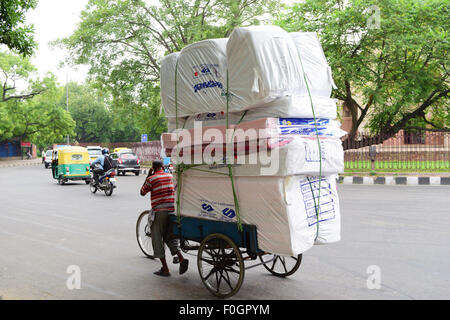 Cycle rickshaw tirato da uomo con le merci pesanti in Delhi India Foto Stock