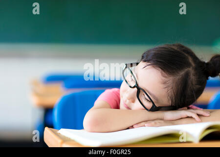 Piccola ragazza dorme indossando occhiali in aula Foto Stock