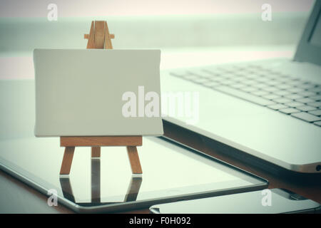 Tela vuota e il cavalletto in legno sul computer portatile come concetto Foto Stock