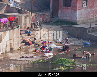 Persone il lavaggio della biancheria a ghat sul fiume Varuna, pratica comune in tutta l'India come molti non hanno accesso all acqua per uso domestico Foto Stock