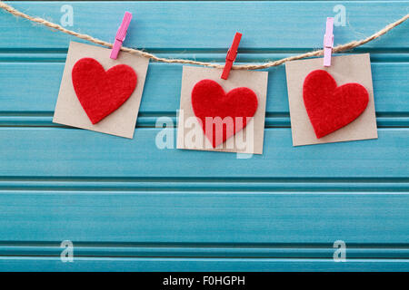 Realizzata a mano con cuori di feltro appeso con clothespins blu su pannello di legno Foto Stock