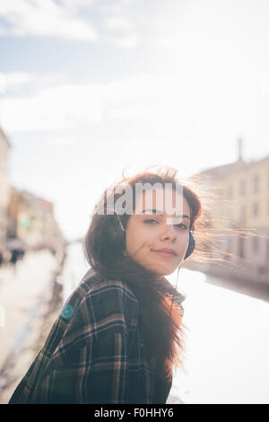 A metà lunghezza della giovane bella marrone rossiccio capelli donna caucasica ascoltando la musica seduto sul marciapiede - relax, musica, Foto Stock