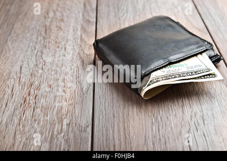 Portafoglio con centinaia di dollari di banconote, su sfondo di legno Foto Stock