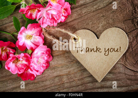 A forma di cuore ringrazio card con fiori su uno sfondo di legno Foto Stock