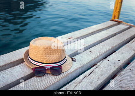 Occhiali da sole, flip-flop e hat sulla texture di legno in estate. Foto Stock