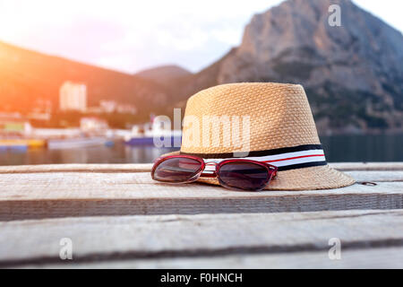 Occhiali da sole, flip-flop e hat sulla texture di legno in estate. Foto Stock