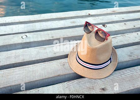 Occhiali da sole, flip-flop e hat sulla texture di legno in estate. Foto Stock