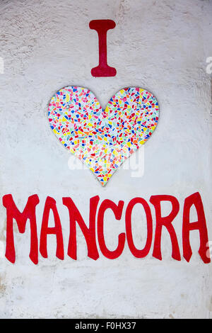 Sullo sfondo di un mosaico di pietra cuore sul muro bianco Mancora, Perù. Il messaggio dice che io amo Mancora. Foto Stock