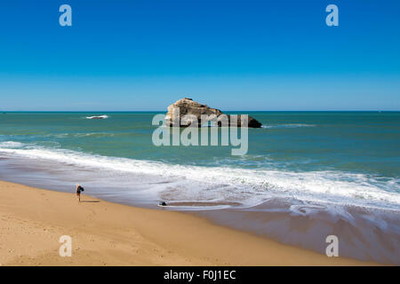 Donna di camminare sulla spiaggia vuota nella spiaggia di Biarritz, rocce e blu oceano, Aquitaine, Francia. Foto Stock