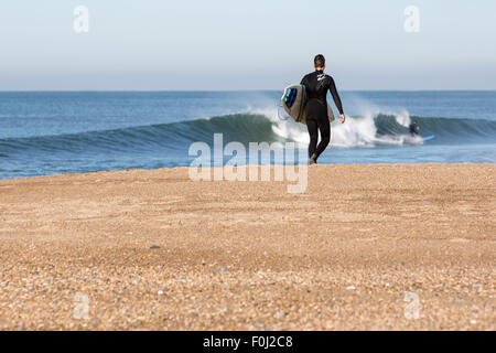 Unidentified giovane con tavola da surf su dicembre 3, 2013. Spiaggia di Biarritz, Francia. Foto Stock