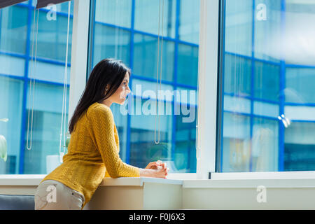 Ritratto di un informale imprenditrice guardando nella finestra di office Foto Stock