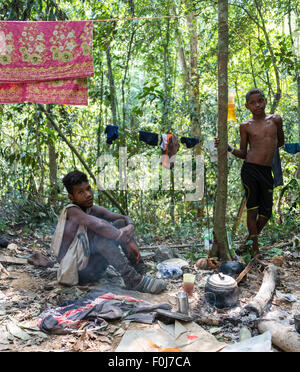 Due giovani uomini di Orang Asil tribù seduto a terra nella giungla e il tè, nativo, popolazioni indigene Foto Stock