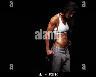 Ritratto di giovane fitness donna con un salto con la corda. Bodybuilder femminile con corda da salto guardando verso il basso. Foto Stock