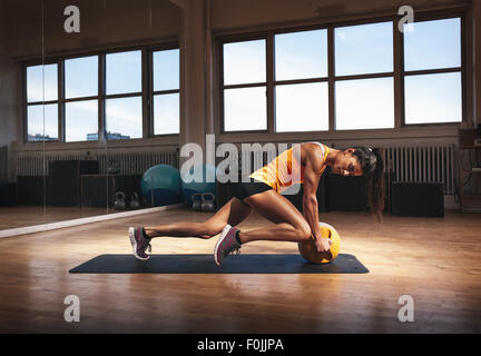 Donna muscolare in palestra a lavorare fuori sul suo corpo di nucleo. Donna forte esercizio con kettlebell nel club sportivo. Foto Stock