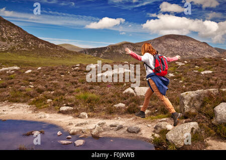 Hill walker saltando un laghetto nel paesaggio di montagna. Foto Stock