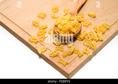 La pasta in forma di animali e un cucchiaio di legno su sfondo bianco Foto Stock