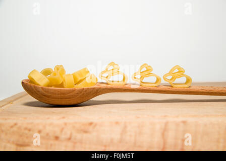 La pasta in forma di animali e un cucchiaio di legno su sfondo bianco Foto Stock